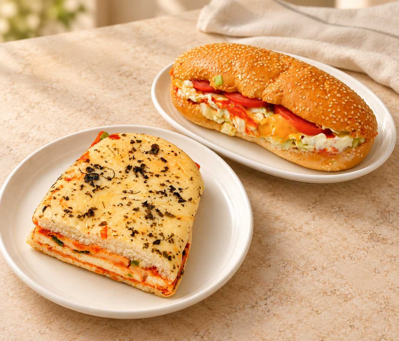Herb-topped sandwich and sesame sub sandwich with vegetable fillings on white plates